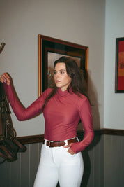 Front view of a female model wearing the cherry blossom Criniere Kai Shirt while standing in a tack room