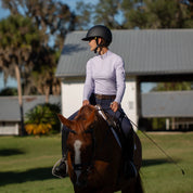 Front view of a female model wearing the navy Equinavia Kristina Knee Patch Breeches while riding a horse outdoors