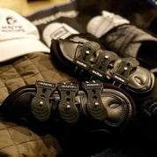 Multiple Majyk Equipe Boyd Martin leather tendon boots arranged together on a quilted surface
