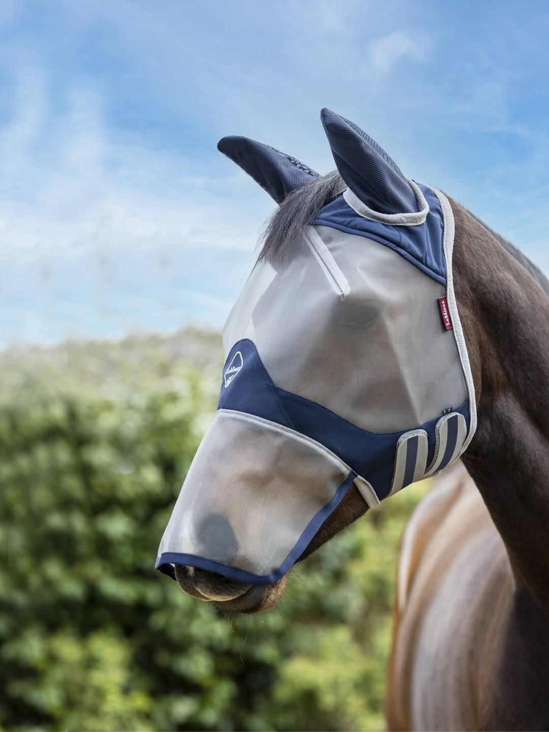 Side view of a dark colored horse wearing the navy Lemieux ArmourShield Pro Full Fly Mask outside