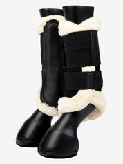 Side view of a pair of black/natural LeMieux Fleece Edged Brushing Boots on plastic horse legs