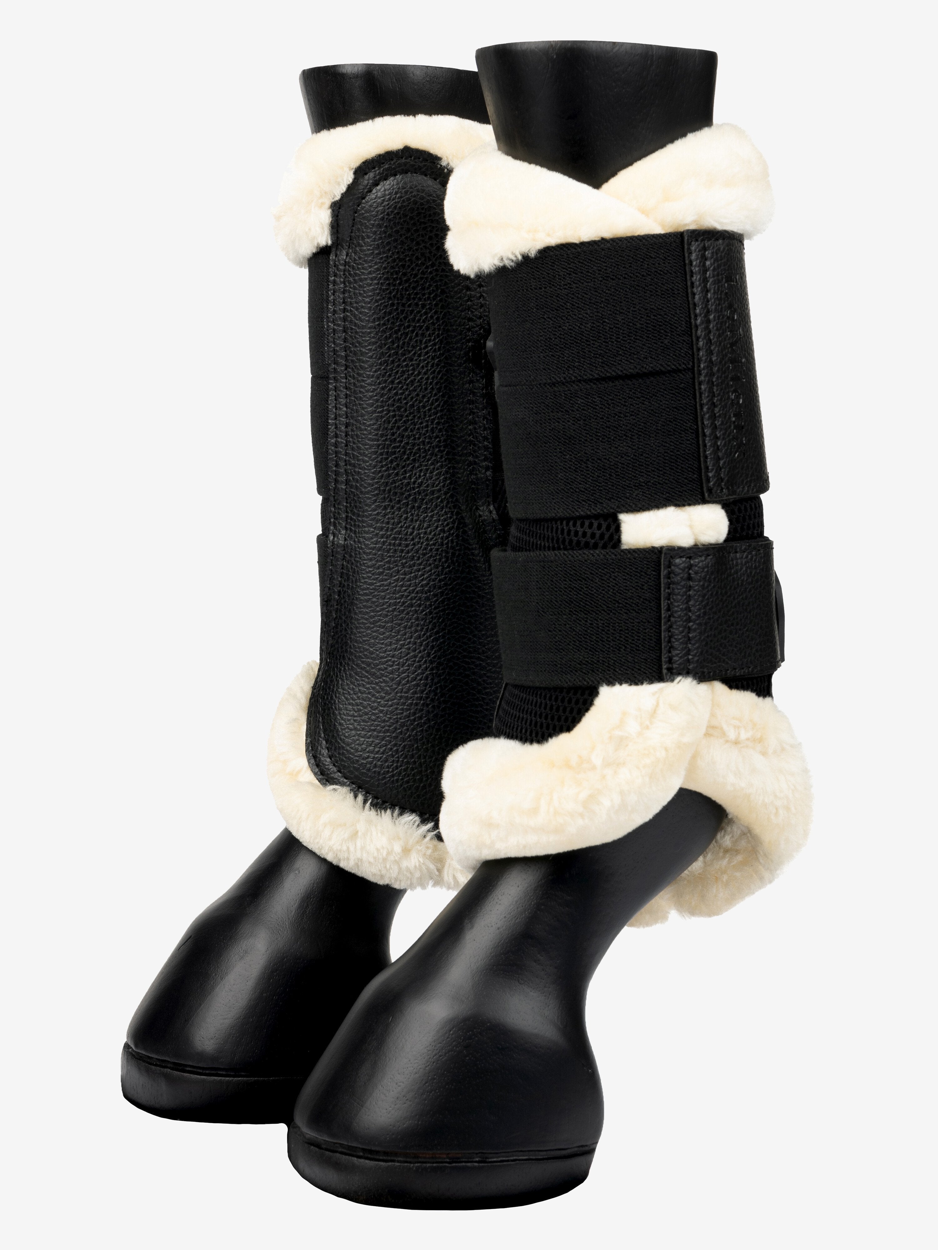 Side view of a pair of black/natural LeMieux Fleece Edged Brushing Boots on plastic horse legs
