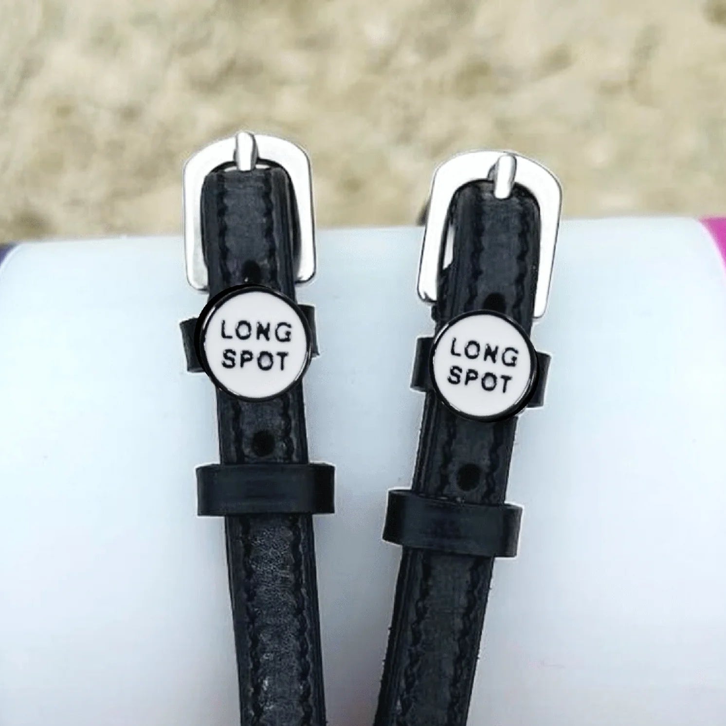 Front view of the buckled Long Spot Mane Jane Spur Straps on a pink, purple, and white pole