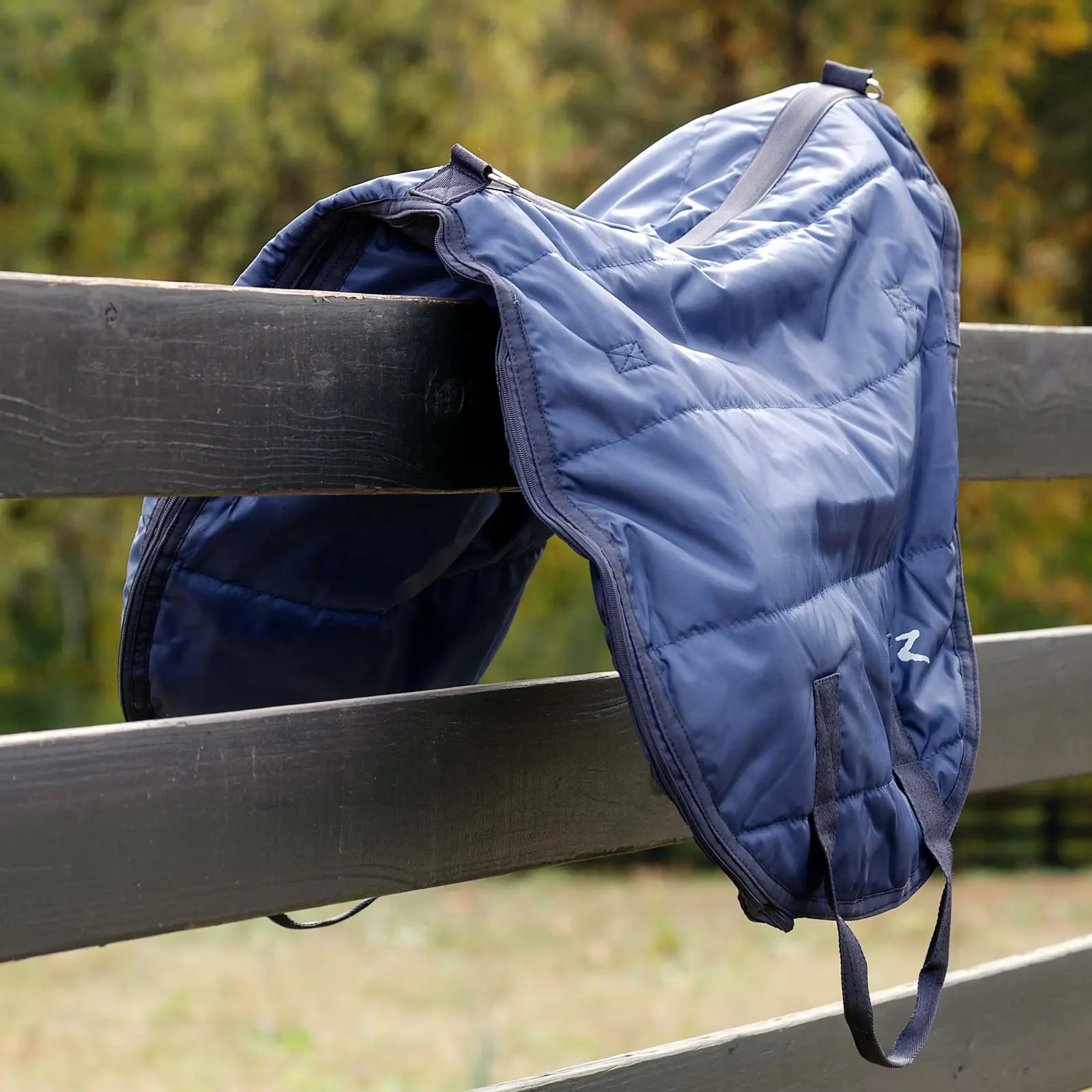 Angled front view of the navy Horze Saddle Bag sitting on a black fence outside