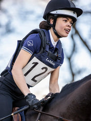 Angled front view of an eventing rider wearing the navy LeMieux Eventing Bib 