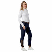 Full body front view of a model wearing the navy Equinavia Maud Knee Patch Breeches, white top, and white tennis shoes on a white background