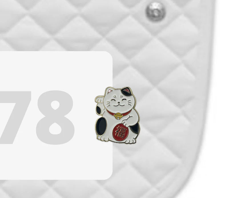 Side view of a white pad with numbers 378 and a Lucky Cat Dubois Cheval Number Pin Charm on a white background