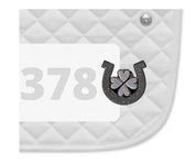Side view of a white pad with numbers 378 and a Horseshoe Clover Dubois Cheval Number Pin Charm on a white background