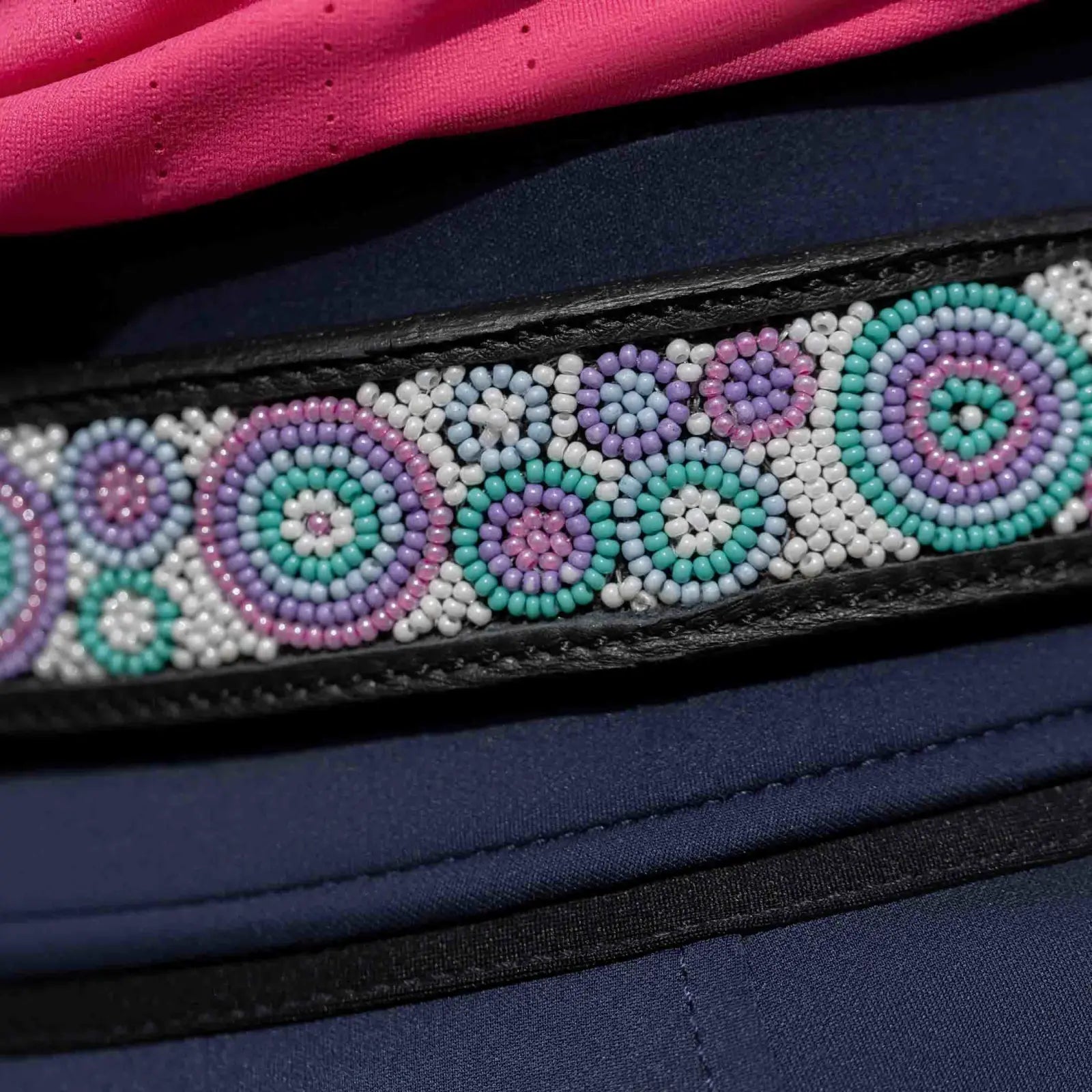 View of a black leather Equinavia Estelle Hand Beaded Belt with turquoise, pink, and purple beading on a navy pair of breeches
