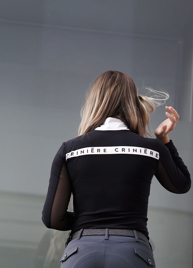 Back view of a female model wearing the Criniere Estella Noir Night Long Sleeve Shirt with a plain background