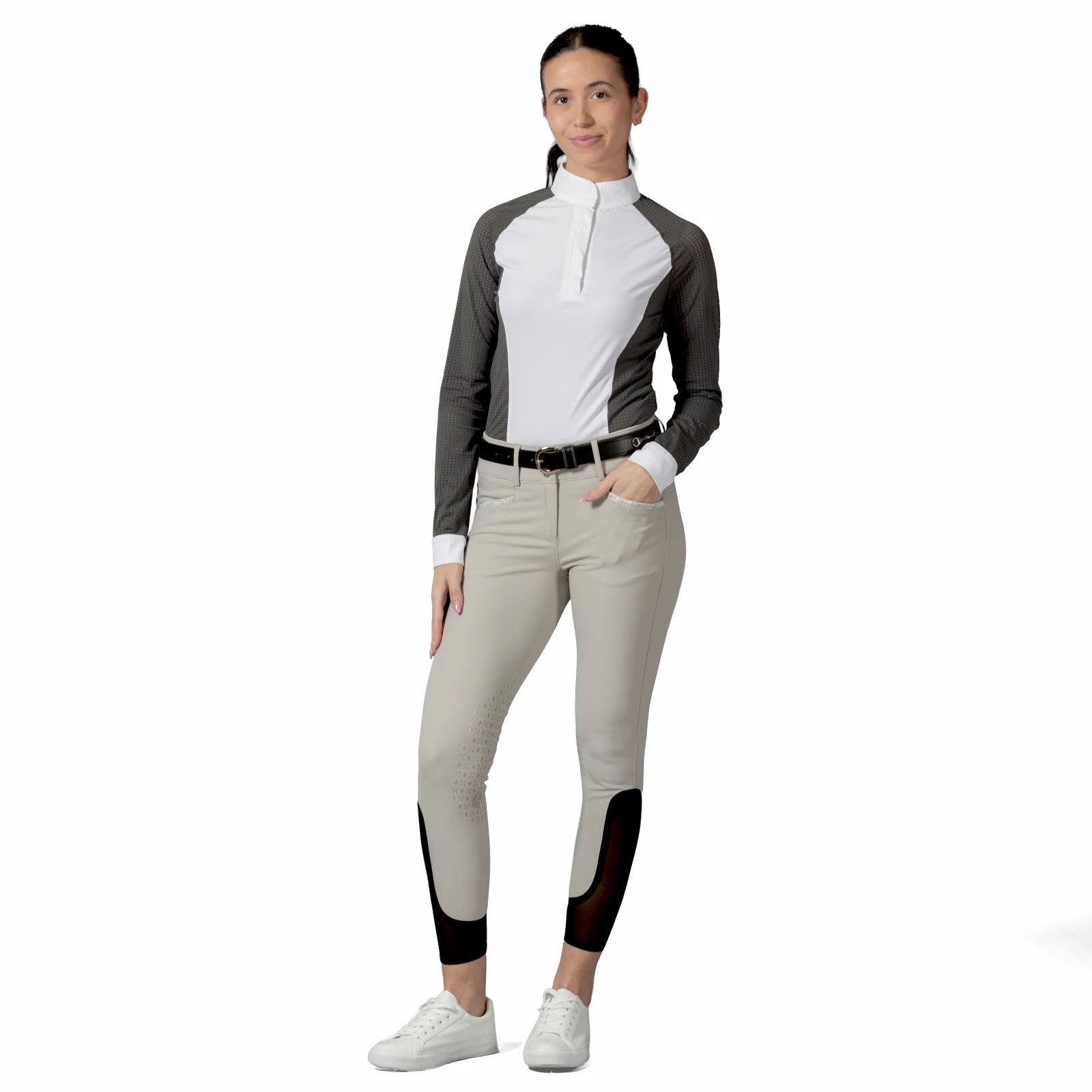 Full body front view of a model wearing the tan Equinavia Kristina Knee Patch Breeches, gray & white show shirt, and white shoes on a white background