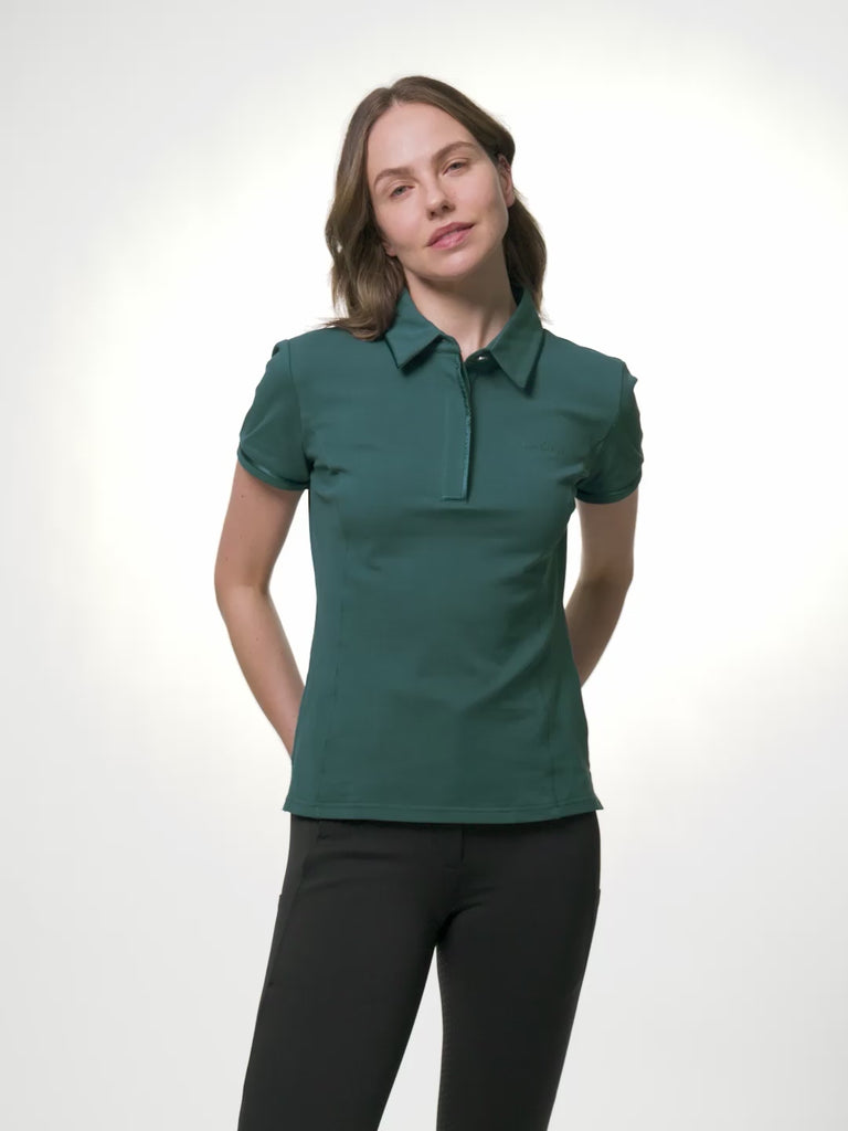 LeMieux Pixie polo shirt in jungle green with pointed collar, partial button placket, sleeve piping, and LeMieux logo on the chest, shown in a video of a model changing poses to show the fit and details against a light gray background.