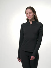 LeMieux Airflow long sleeve base layer in black with quarter-zip high collar, shown on a model moving through different poses to highlight the fit and seam details against a light gray background.