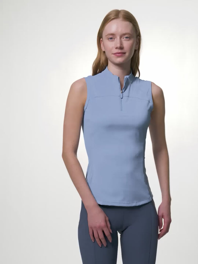 LeMieux Airflow sleeveless base layer in powder blue with quarter-zip high collar, shown in a video of a model changing poses to highlight the fit and seam details against a light gray background.