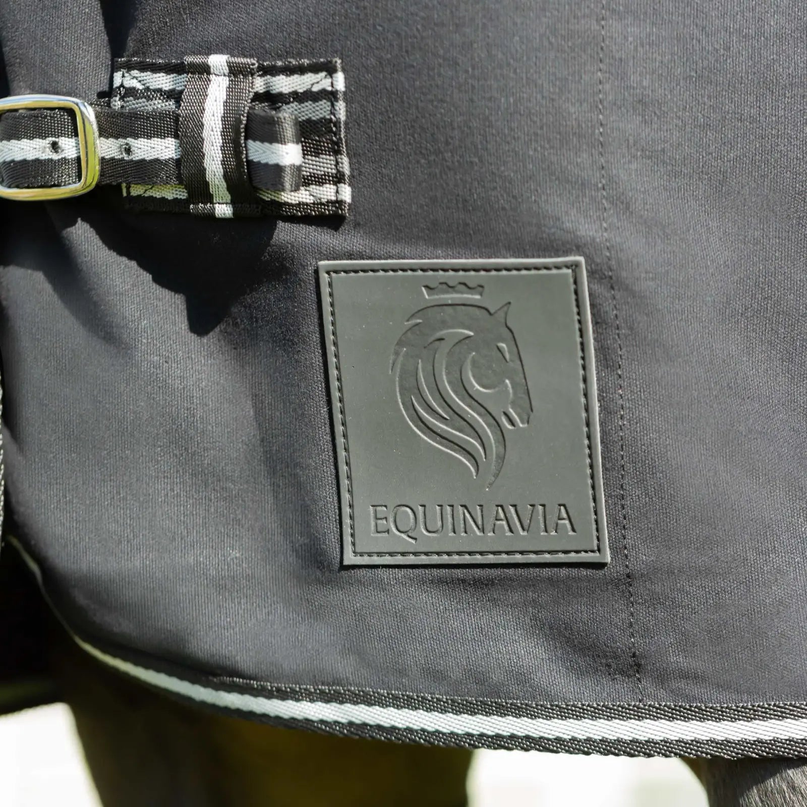 Close-up view of the Equinavia logo on the chest of the black Equinavia Fryd Cotton Stable Sheet