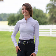 Front view of a model standing outside wearing a purple top and the purple and gray, black-leather Equinavia Siri Polo Belt on black breeches