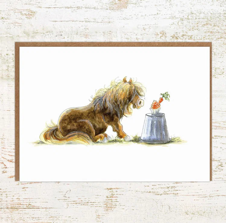 View of the Cupcake Pony Pony Nut Greeting Card on a white washed wood background