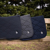 Side view of various colors of the Swarovski Samshield Spineshield Jump Pad  hanging on a wood fence outside