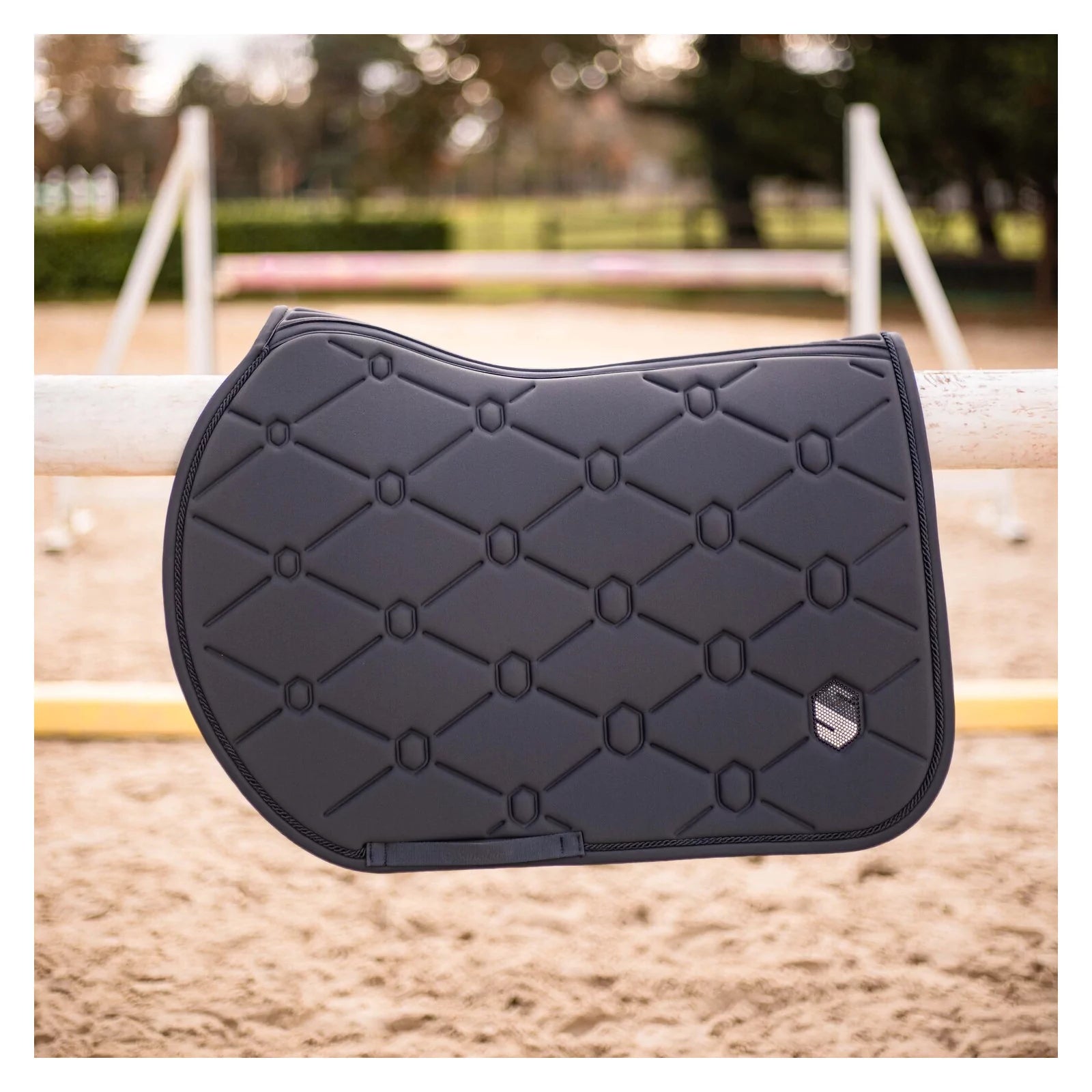 Side view of the anthracite swarovski embroidered Samshield Spineshield Jump Pad hanging over a jump in an outdoor arena