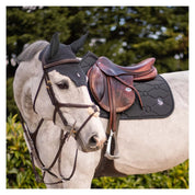 Side view of a gray horse wearing the anthracite swarovski embroidered Samshield Spineshield Jump Pad while standing outside
