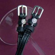 Close-up view of the Silver Wine Glass Mane Jane Spur Straps resting on a clear wine glass on a purple background 
