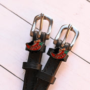 Close-up view of the Spicy Pepper Mane Jane Spur Straps on a white wood plank background