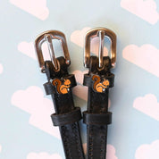 Close-up view of the Squirrel Mane Jane Spur Straps on a blue sky background