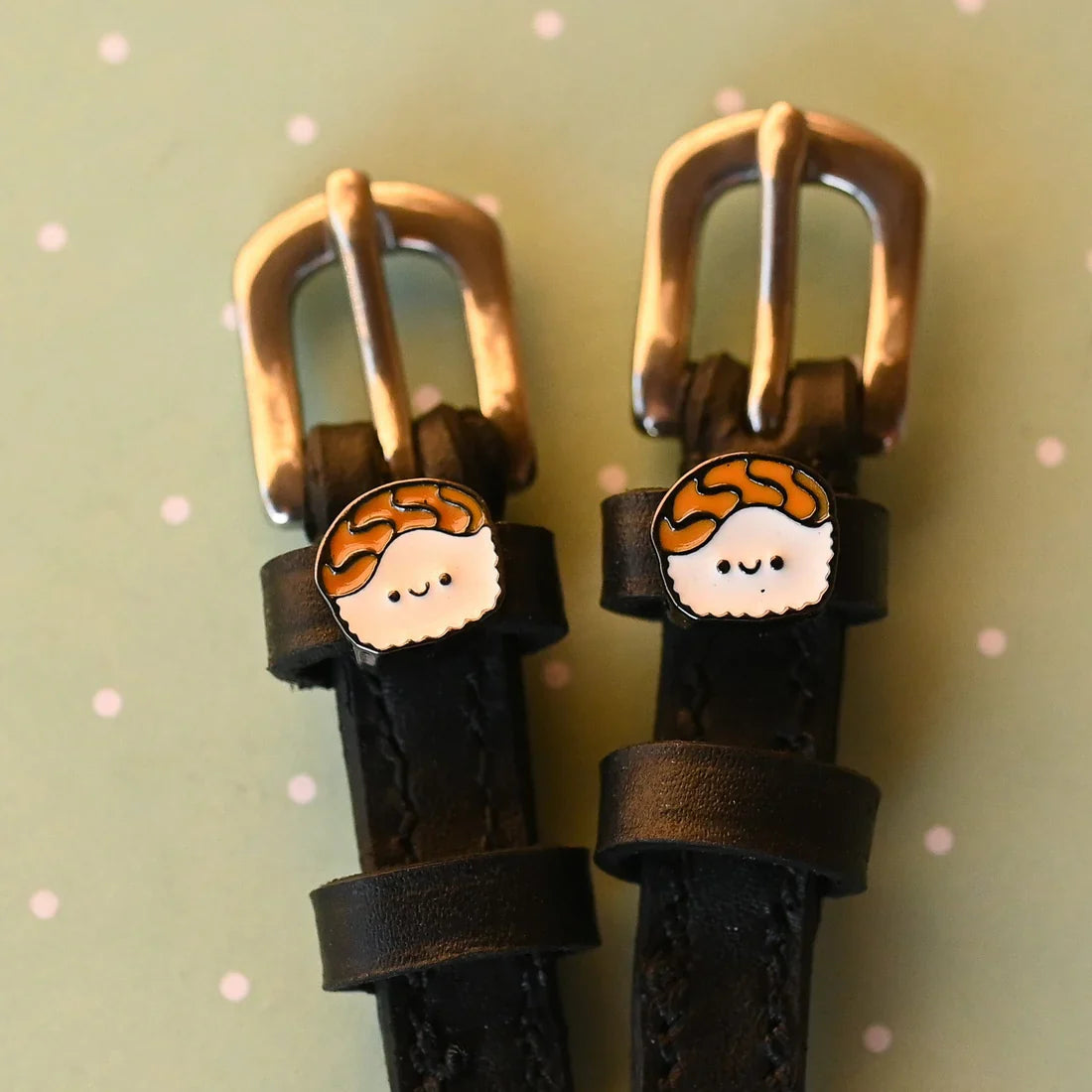 Close-up view of the Sushi Mane Jane Spur Straps on a green background with white polka dots