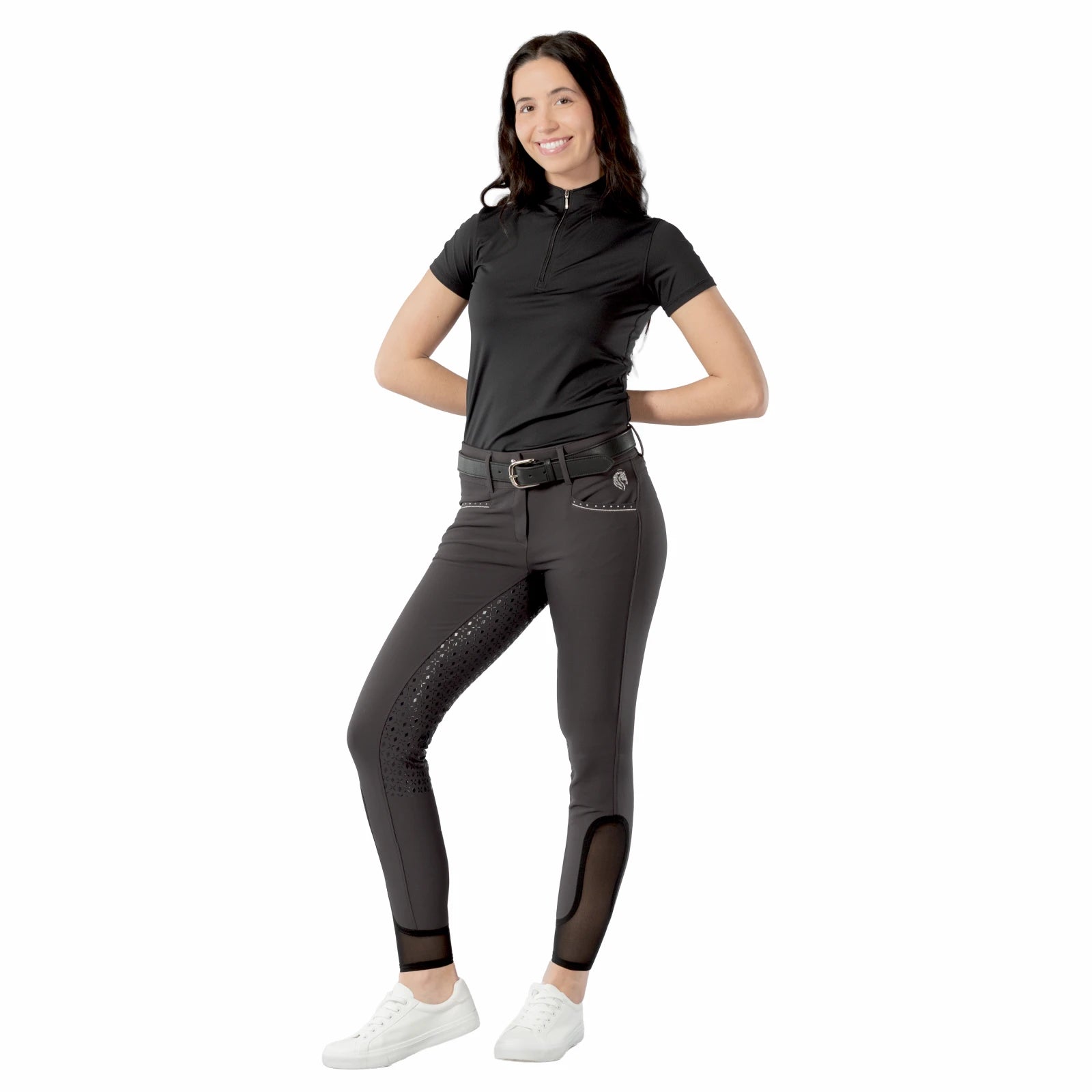 Full body front view of model wearing the dark gray Equinavia Victoria Full Seat Breeches, black top, and white shoes on a white background