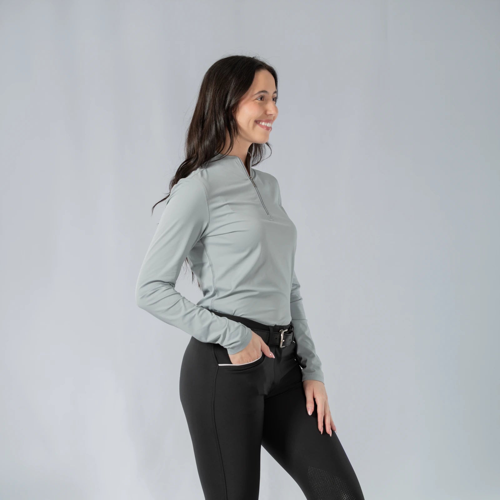 Angled front view of a model wearing the Equinavia Kari Womens Long Sleeve Sun Shirt with NordicAir Tech in gray on a gray background