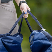 Close-up view of a model holding the handles on the navy Horze Saddle Bag