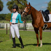 Front view of a model wearing the Equinavia Astrid Full Seat Breeches in white, while standingnext to a horse