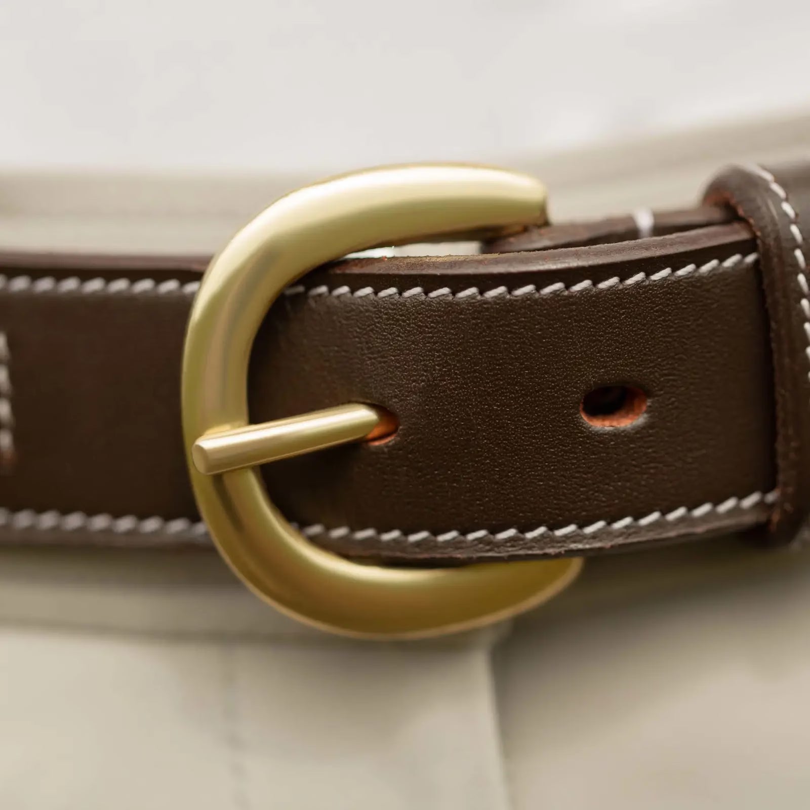 Close-up view of the buckle on the brown Equinavia Filippa Fancy Stitch Bit Belt over tan breeches