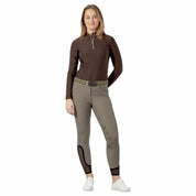 Full body front view of a model wearing the sage olive Equinavia Maud Knee Patch Breeches, brown top, and white tennis shoes on a white background