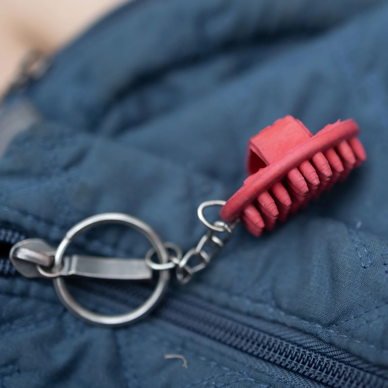 View of the red Horze Brush Key Chain on a blue zipper