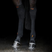 View of a horse wearing a pair of Incrediwear Circulation Hock Sleeves on a black background