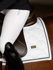 Close-up side view of a model riding a horse with a white Equestrian Stockholm White Perfection Dressage Pad