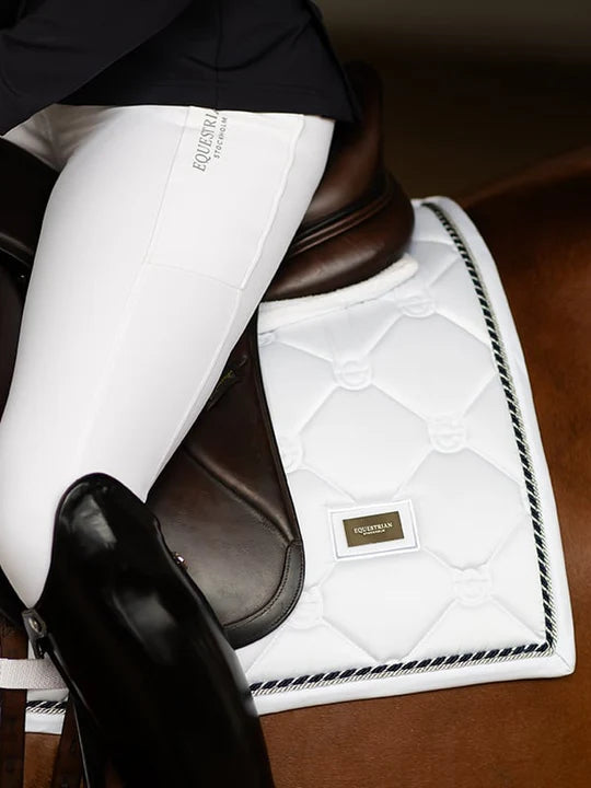 Close-up side view of a model riding a horse with a white Equestrian Stockholm White Perfection Dressage Pad