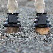 Black Equinavia Step Guard Rubber Bell Boots on a gray horse standing on gravel