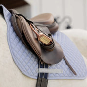 Close-up view of the girth keeper on the gray Equinavia Harstad All Purpose Pad under a brown saddle and on a gray horse